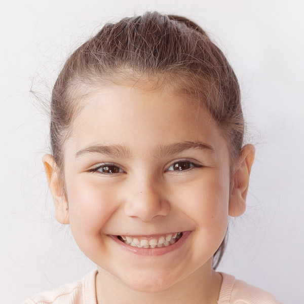 A smiling girl with long hair beams with joy, showcasing her cheerful personality.