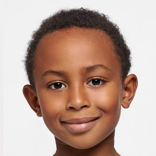 A boy with a warm smile and short hair presents a confident expression.