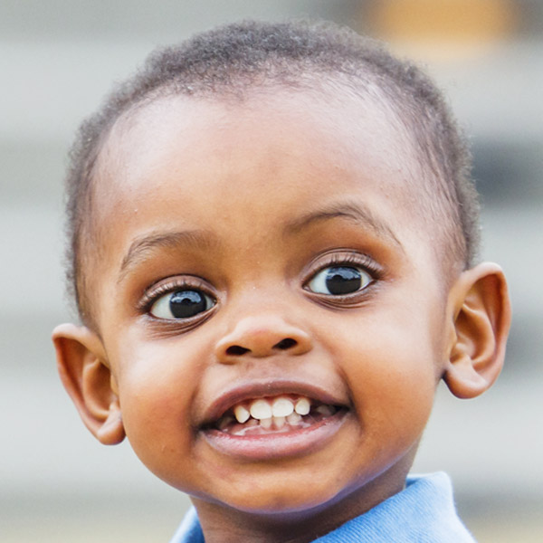 A young boy grins widely, showcasing his playful spirit and bright eyes.