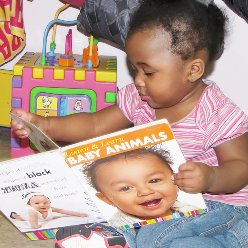 A child explores a colorful book about baby animals, captivated by the images and text.